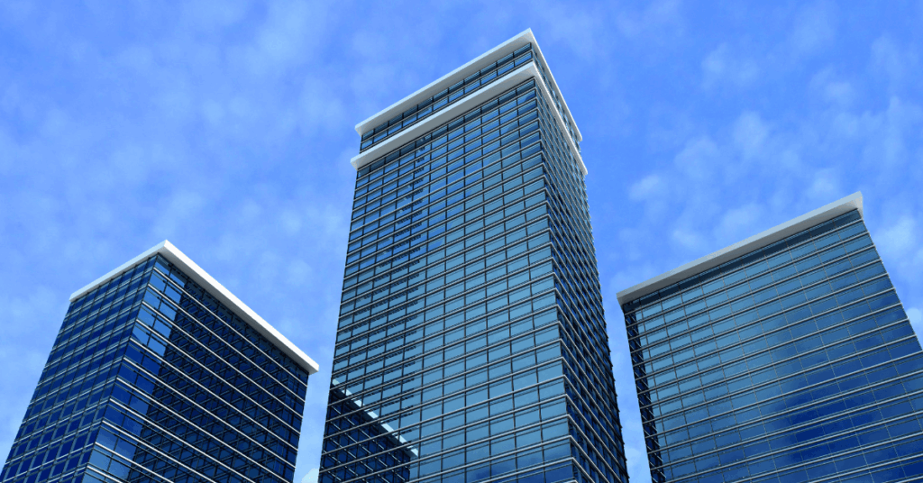 Fachada de prédios comerciais espelhados representando investimentos imobiliários, ilustrando o fundo KNSC11 e o mercado de FIIs de papel em 2025.