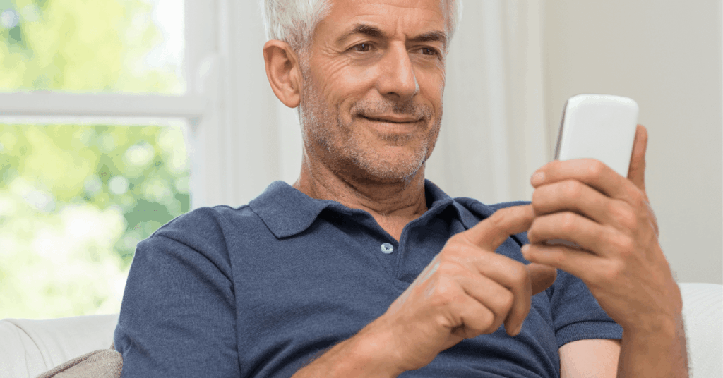 Homem maduro com cabelo grisalho usando celular para acompanhar investimentos em FIIs voltados para aposentadoria.
